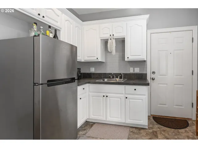 a kitchen with stainless steel appliances granite countertop a refrigerator a stove and white cabinets