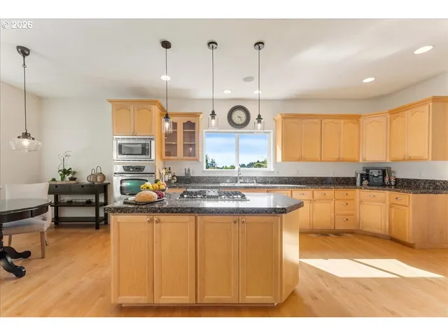a kitchen with stainless steel appliances granite countertop a sink a stove and a wooden floors