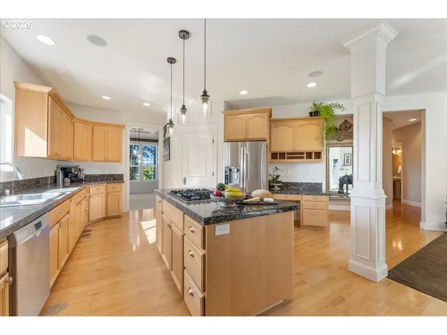 a kitchen with stainless steel appliances kitchen island granite countertop a stove a sink and a refrigerator