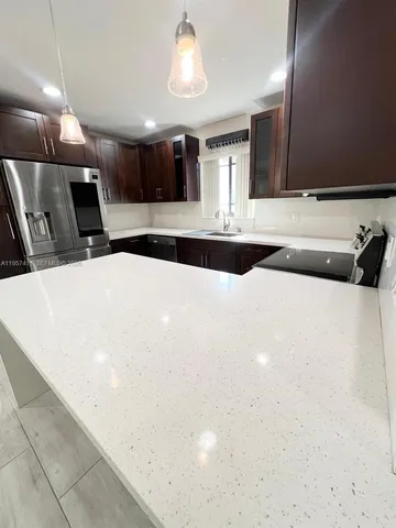 a large white kitchen with a large island oven a sink with wooden cabinets and floor
