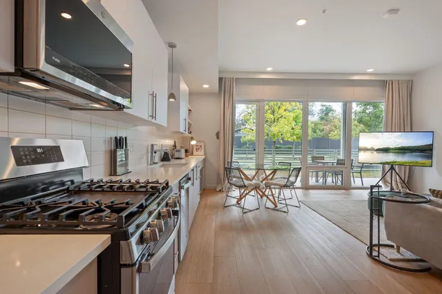 a kitchen with a table chairs stove and wooden floor