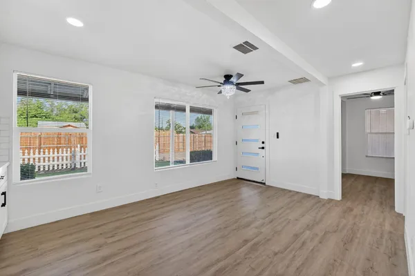 a view of an empty room with wooden floor and a window