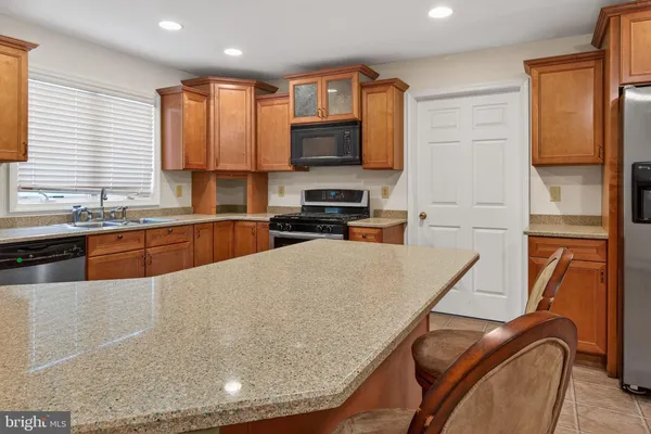 a kitchen with stainless steel appliances granite countertop a stove top oven a sink a dining table and chairs