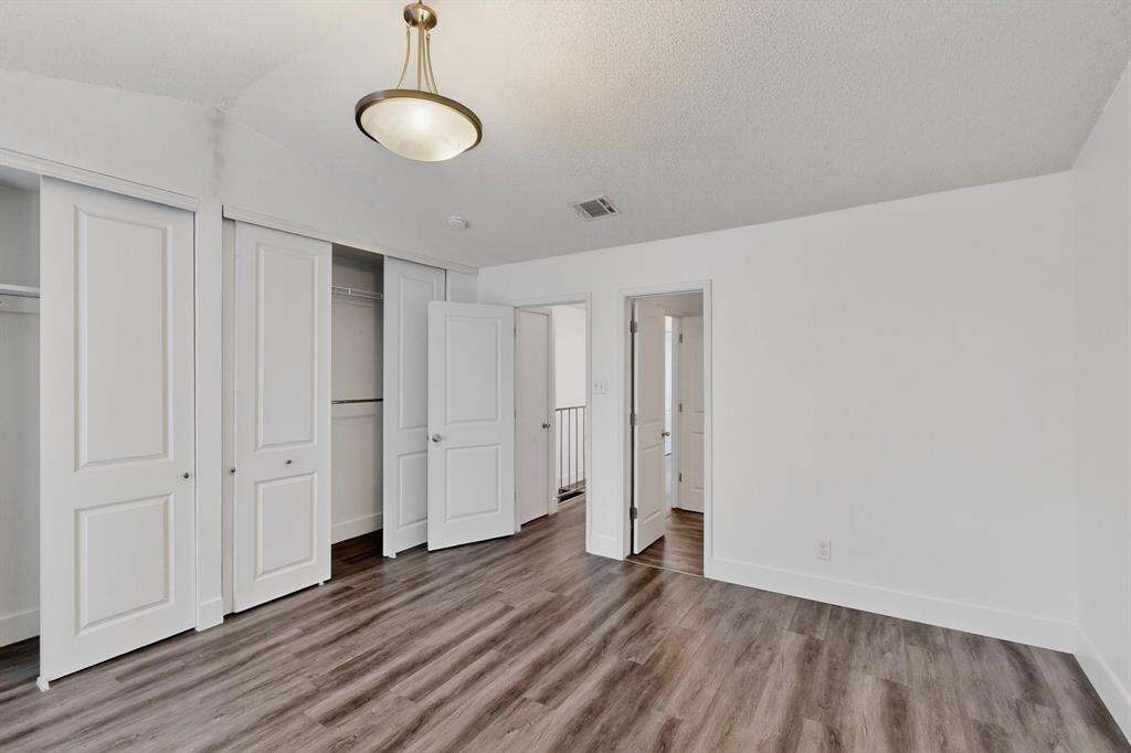 46 Abbey Road Euless, TX 76039 - Photo 9 of 16 Unfurnished bedroom with multiple closets, light wood-style flooring, and a textured ceiling