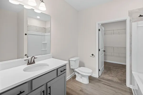 a bathroom with a sink a toilet a shower and a large mirror