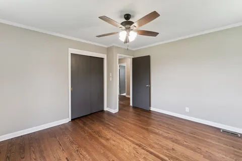 an empty room with wooden floor and ceiling fan