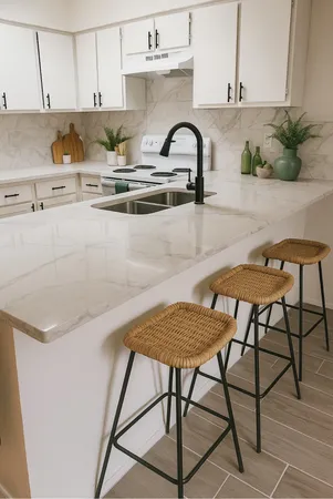 a kitchen with stainless steel appliances granite countertop a table chairs in it and white cabinets