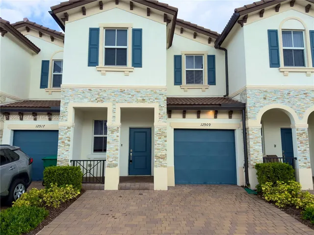 a front view of a house with yard and parking