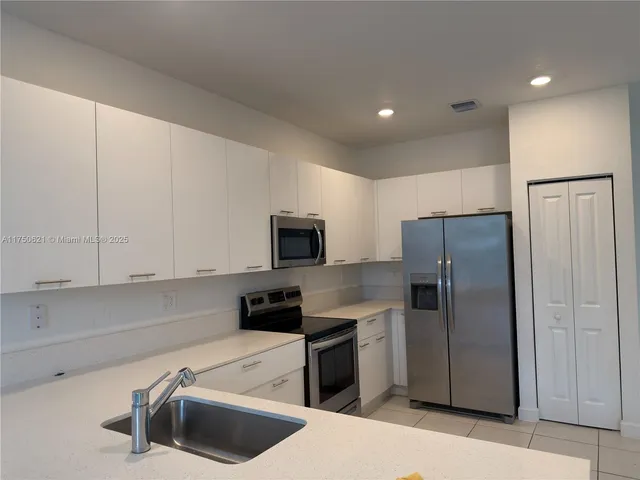 a kitchen with stainless steel appliances a refrigerator a sink a stove a microwave a counter top and cabinets