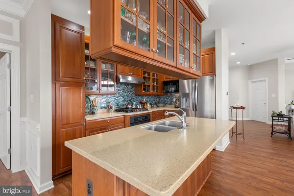 a kitchen with stainless steel appliances kitchen island granite countertop a large kitchen island a stove a refrigerator a sink dishwasher a dining table and chairs with wooden floor