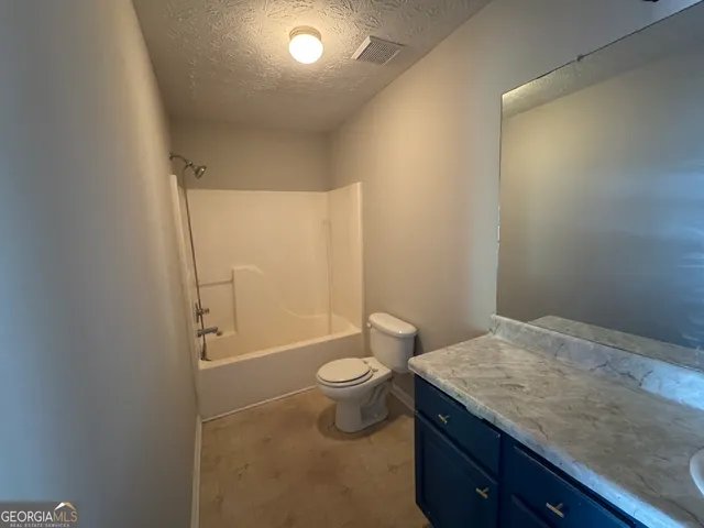 a bathroom with a granite countertop sink a toilet and shower