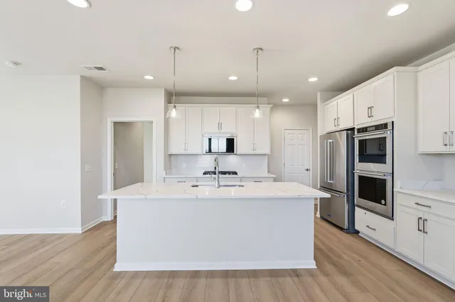 a large white kitchen with kitchen island a sink appliances and cabinets