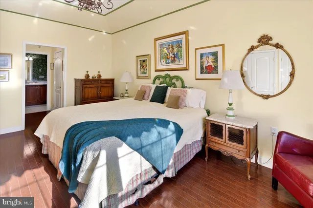 a bedroom with a bed a mirror on dresser and a wooden floor
