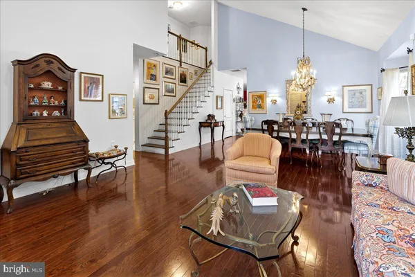 a living room with couches chairs and a dining table with wooden floor