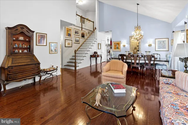 a living room with couches chairs and a dining table with wooden floor