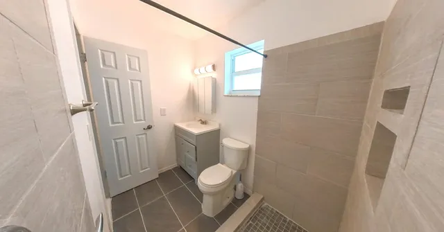 a white toilet sitting next to a shower