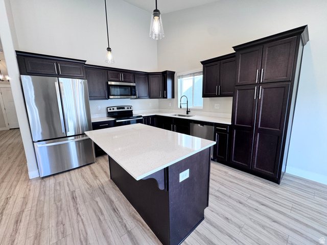 12339 Remy Road, Unit 422 Herriman, UT 84096 - Photo 11 of 36 Kitchen featuring a high ceiling, stainless steel appliances, a kitchen island, light wood-style floors, and light stone counters