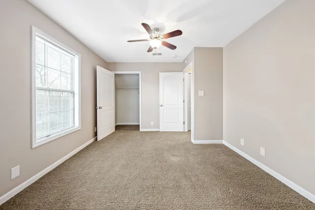 an empty room with window and ceiling fan