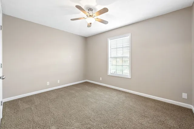 an empty room with a window and a ceiling fan