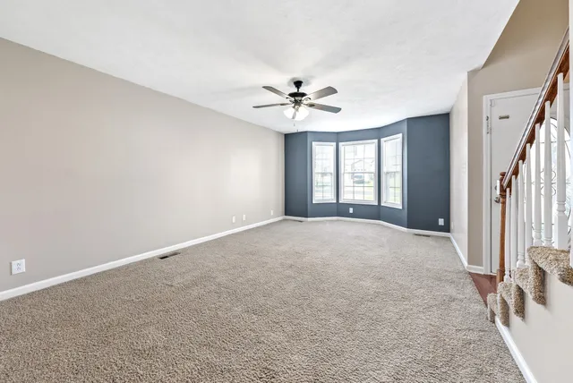 an empty room with windows and ceiling fan