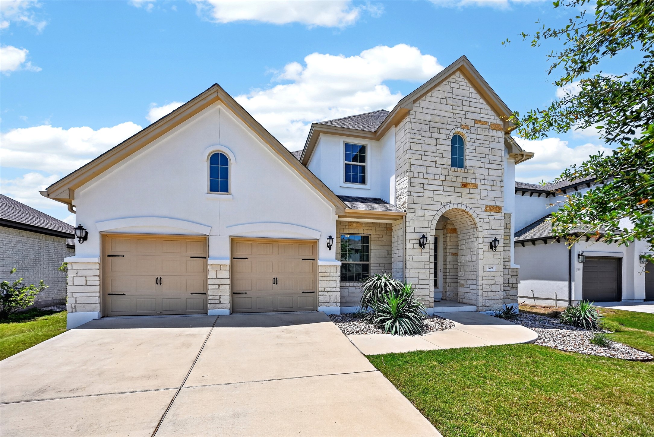 1201 Positano Pass Leander, TX 78641 - Photo 3 of 40 Stucco and stone facade with an arched entry and twin garage doors
