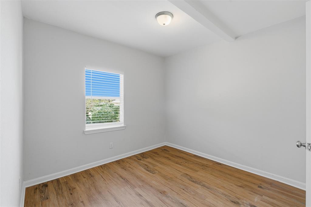 215 North Morrow Street Blue Ridge, TX 75424 - Photo 18 of 23 Empty room with wood finished floors and beam ceiling