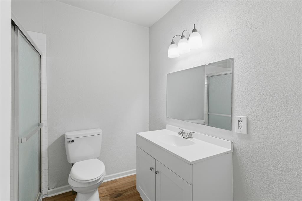 215 North Morrow Street Blue Ridge, TX 75424 - Photo 21 of 23 Full bathroom with vanity, wood finished floors, a shower stall, and a textured wall