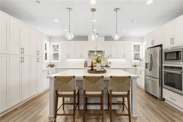 a kitchen with stainless steel appliances kitchen island a table chairs and a refrigerator