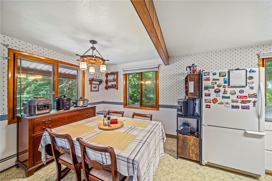 719 Howard Road Ashtabula, OH 44004 - Photo 11 of 43 Dining area featuring wallpapered walls, beamed ceiling, light floors, a chandelier, and baseboard heating
