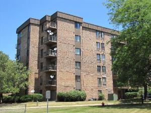 a front view of a building with a yard and large trees
