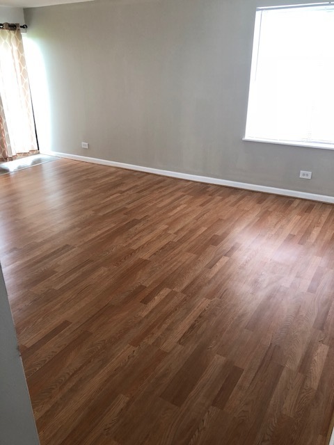 425 Walnut Creek Road, Unit 1608 Lisle, IL 60532 - Photo 4 of 13 an empty room with wooden floor and windows