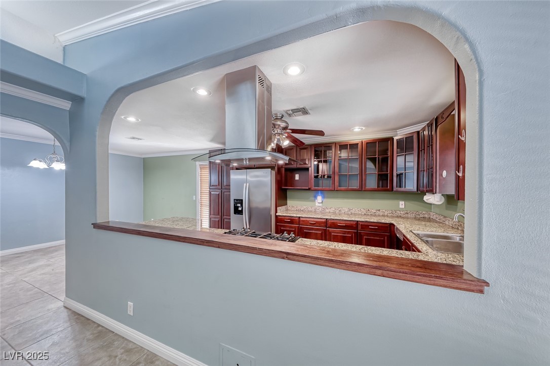 632 Arrayo Way Boulder City, NV 89005 - Photo 13 of 40 Kitchen featuring appliances with stainless steel finishes, ornamental molding, island range hood, arched walkways, and a sink