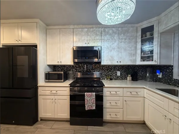 a kitchen with white cabinets and black appliances