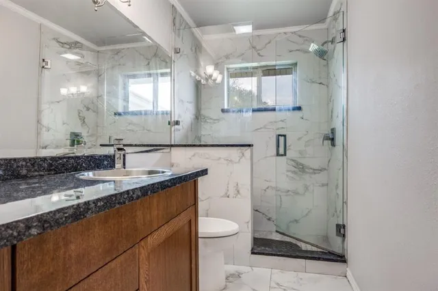 a bathroom with a granite countertop sink toilet a mirror and shower