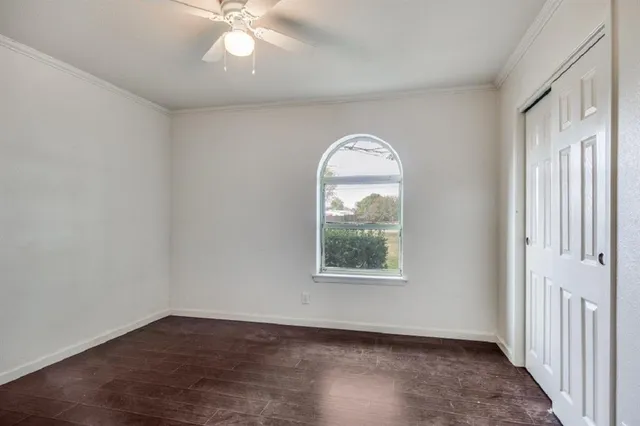an empty room with wooden floor fan and windows