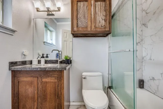 a bathroom with a granite countertop toilet a sink and a mirror