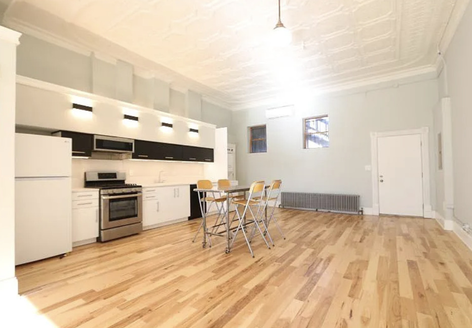 1316 West Erie Street, Unit 1E Chicago, IL 60642 - Photo 5 of 12 a kitchen with stainless steel appliances a stove top oven a sink dishwasher and a dining table with wooden floor