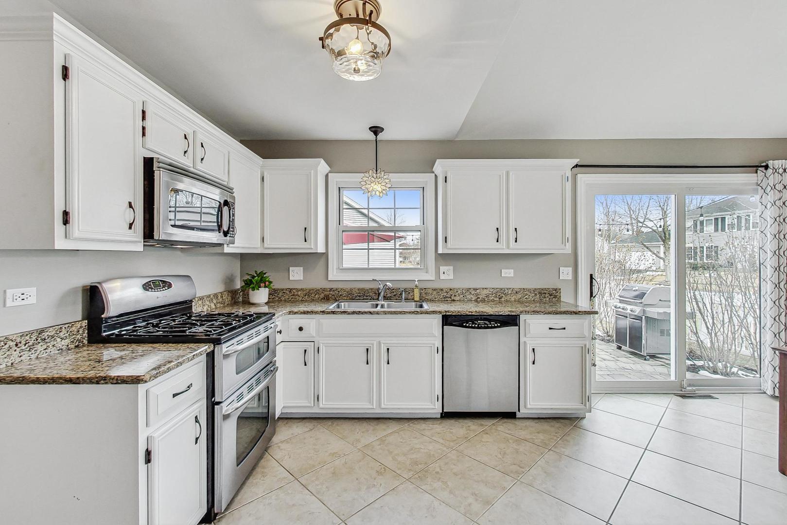 1345 East Bailey Road Naperville, IL 60565 - Photo 9 of 49 a kitchen with granite countertop white cabinets a sink a stove a dining table and chairs