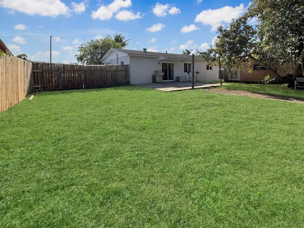 a view of a house with a yard and large trees