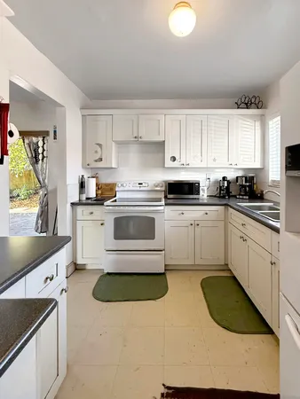 a kitchen with a sink white cabinets and white appliances