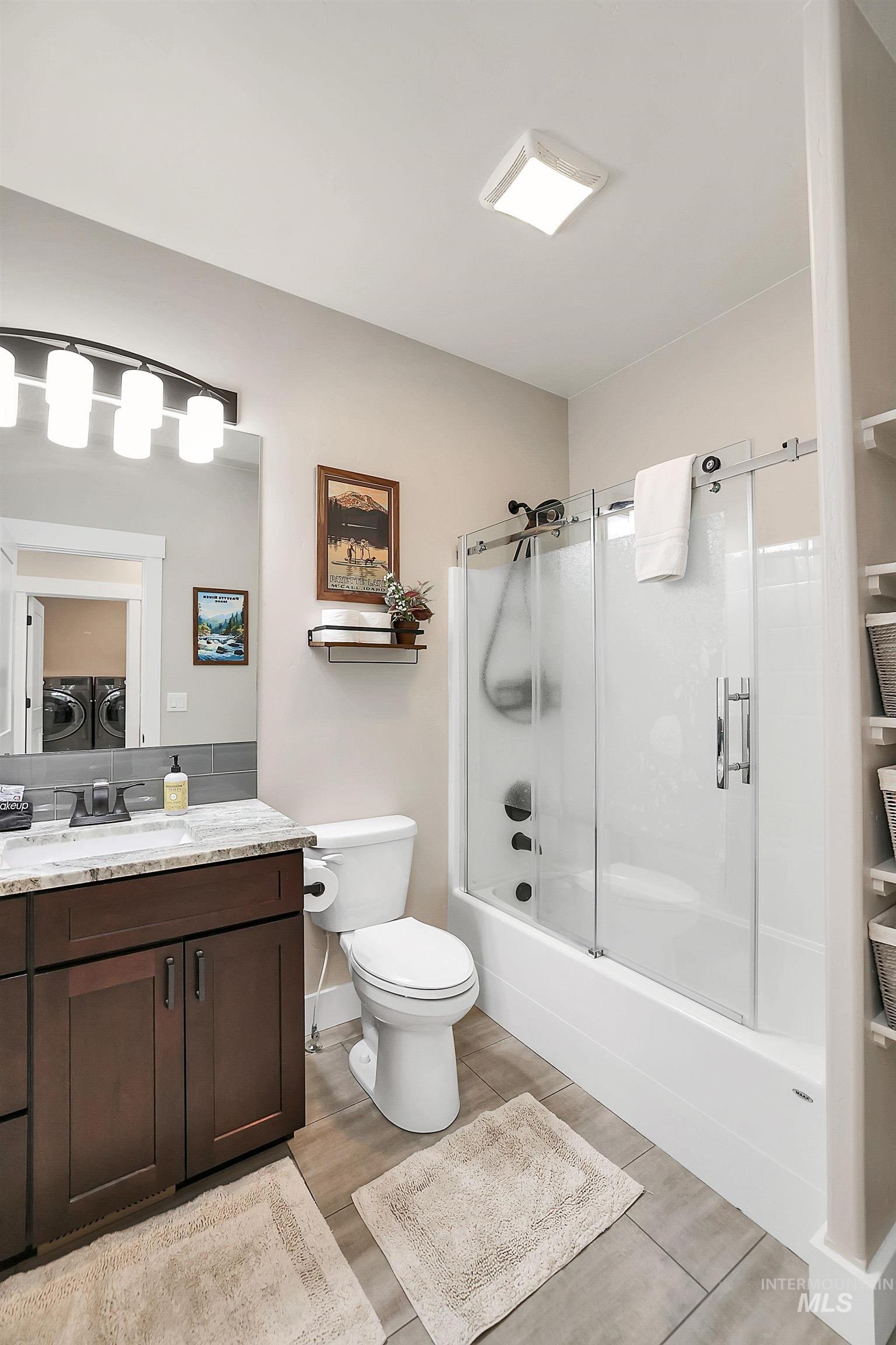 609 Blue Water Circle McCall, ID 83638 - Photo 29 of 45 Bathroom featuring vanity, light wood finished floors, shower / bath combination with glass door, and separate washer and dryer