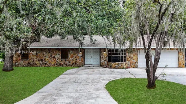 a front view of a house with a garden and trees