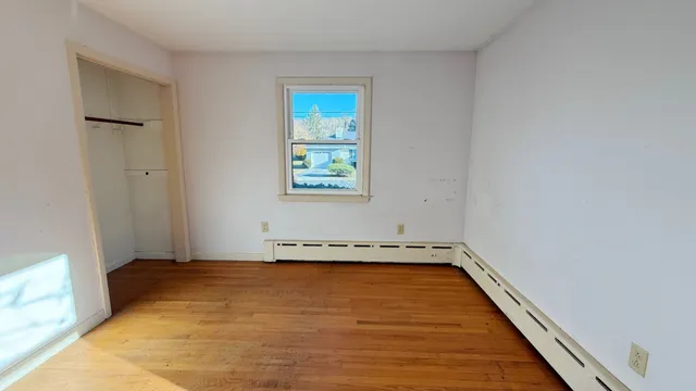 an empty room with wooden floor and window