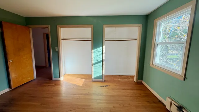 a view of empty room with wooden floor and window