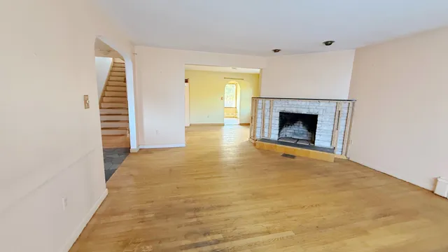 a view of empty room with fireplace and wooden floor