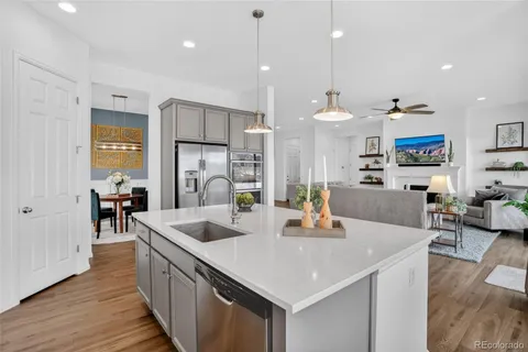 a kitchen with stainless steel appliances granite countertop a sink a stove and a wooden floors