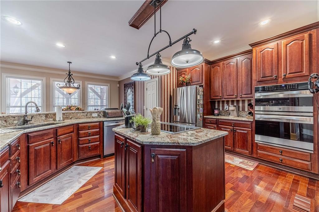 686 Newton Factory Bridge Road Covington, GA 30014 - Photo 12 of 110 a kitchen with stainless steel appliances kitchen island granite countertop a stove a sink dishwasher and a refrigerator with wooden cabinets