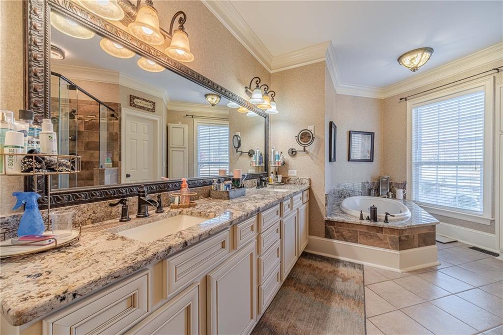 686 Newton Factory Bridge Road Covington, GA 30014 - Photo 31 of 110 a bathroom with a granite countertop sink a large mirror and a bathtub next to a window