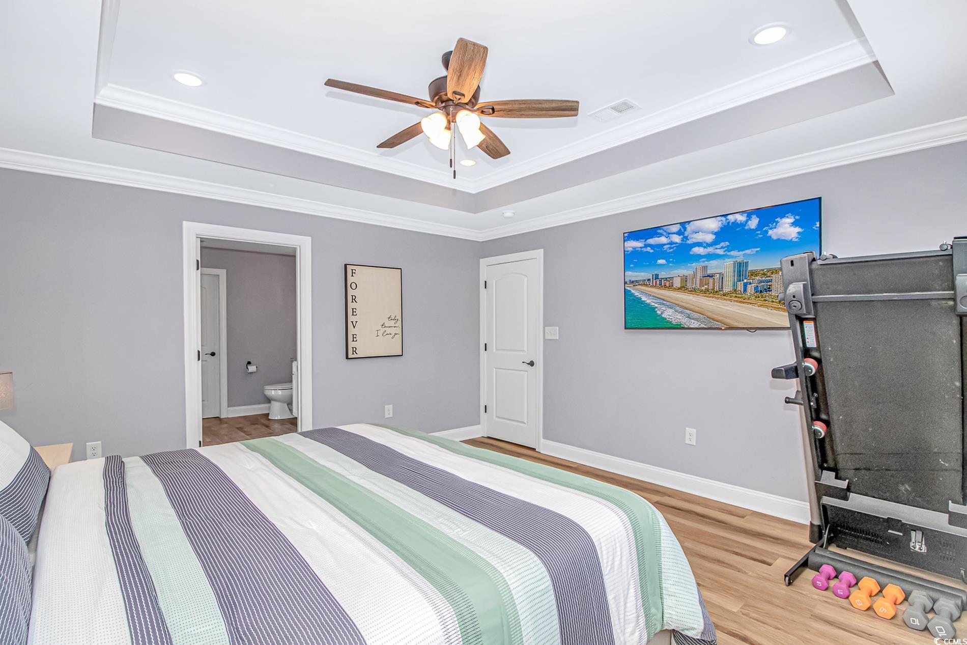 4082 Edwards Road Aynor, SC 29511 - Photo 21 of 40 Bedroom featuring a raised ceiling, crown molding, light wood-style floors, a ceiling fan, and connected bathroom