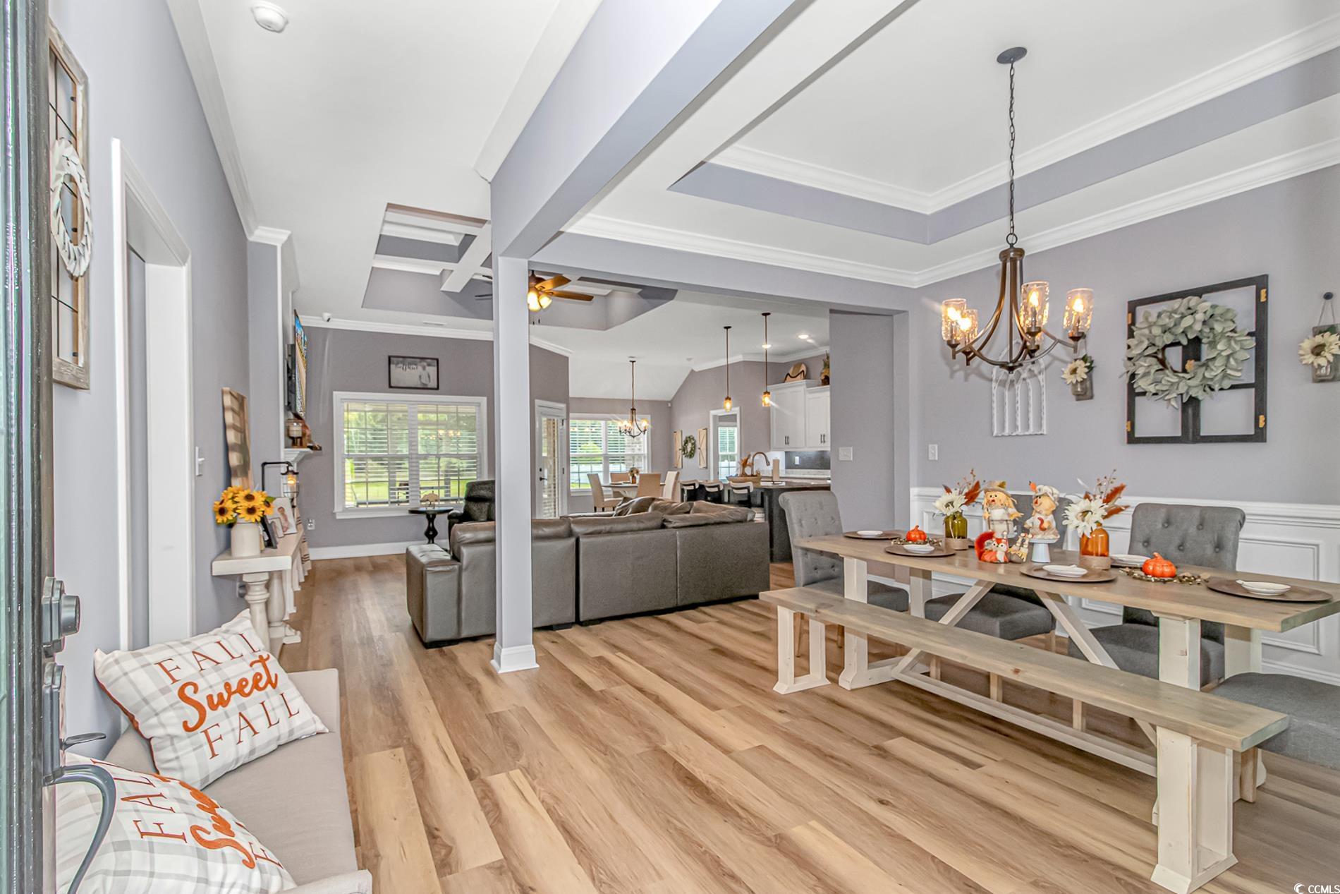 4082 Edwards Road Aynor, SC 29511 - Photo 3 of 40 Dining space featuring a chandelier, ceiling fan, light wood-type flooring, ornamental molding, and a tray ceiling